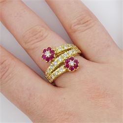18ct gold ruby and diamond flower head crossover ring, two flowers each set with a single round brilliant cut diamond and six rubies, to diamond set stems and spaced by a row of nine diamonds, stamped 750, total diamond weight approx 0.55 carat