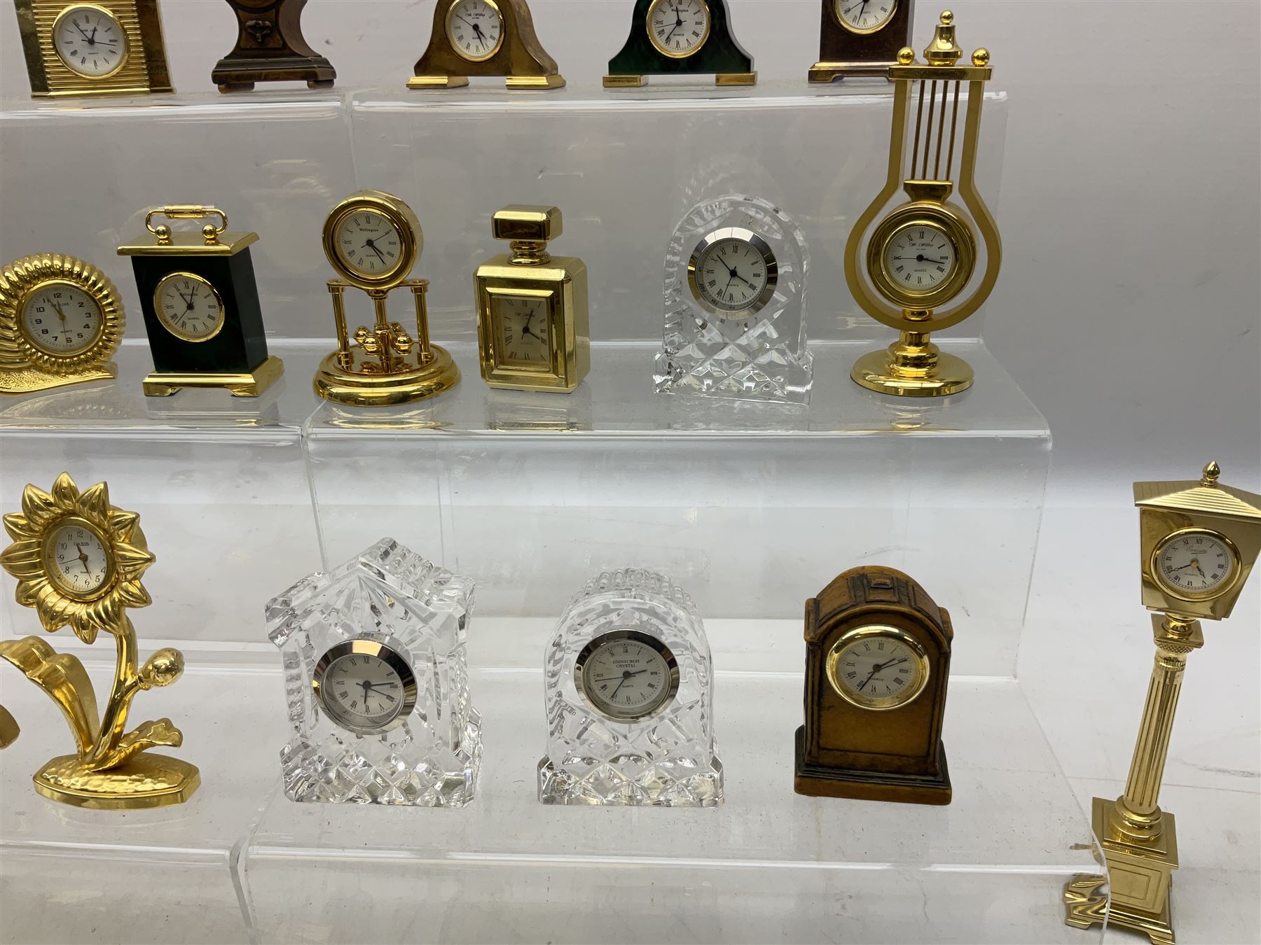 Collection of miniature clocks, predominantly with quartz movements, to include example modelled as an armchair, Edinburgh crystal glass example, clock modelled as a flower, sewing machine etc