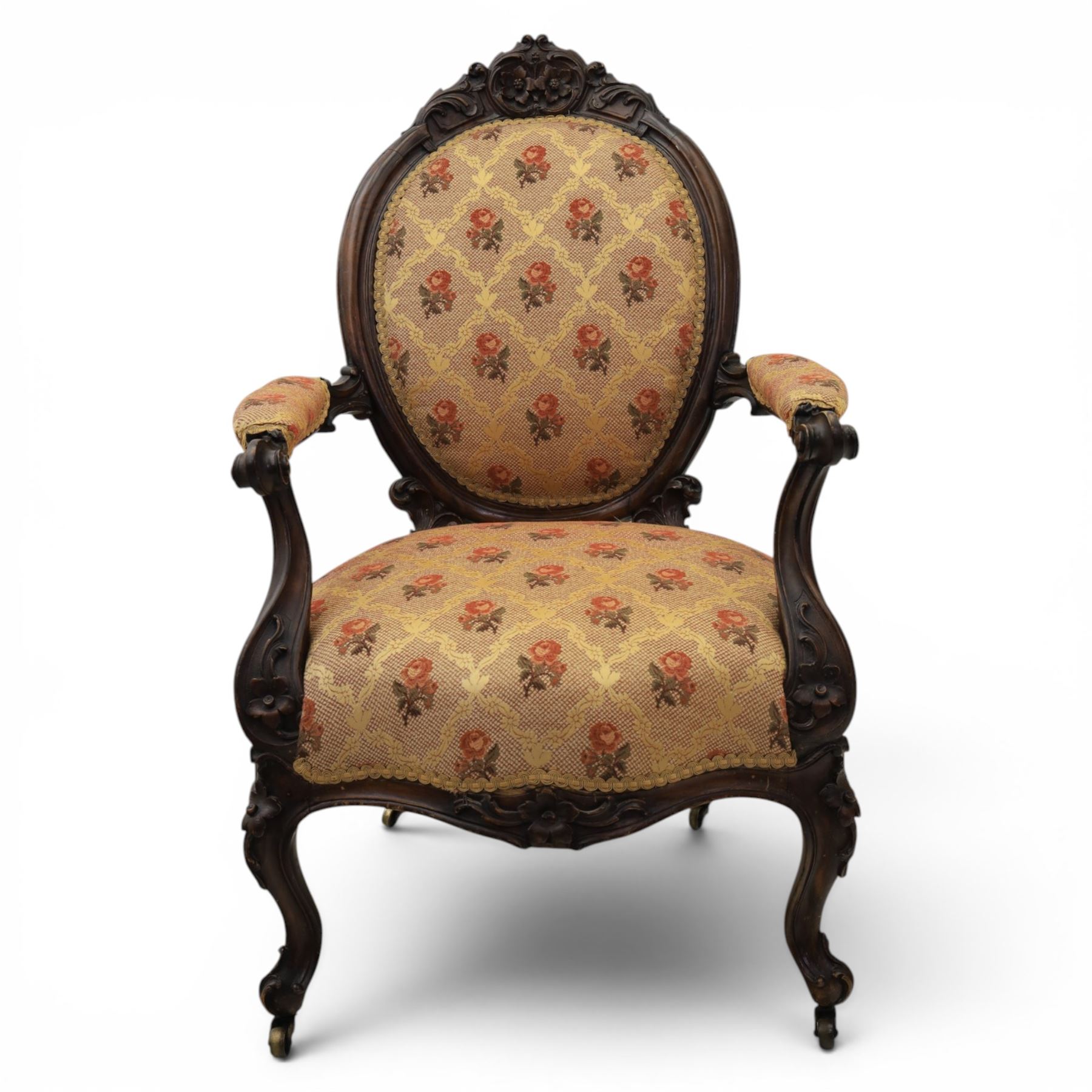 Victorian mahogany open armchair, oval stuff-over back with floral upholstery, moulded and foliate carved frame with pierced crest, padded open arms with scroll terminals, serpentine seat rail on cabriole supports