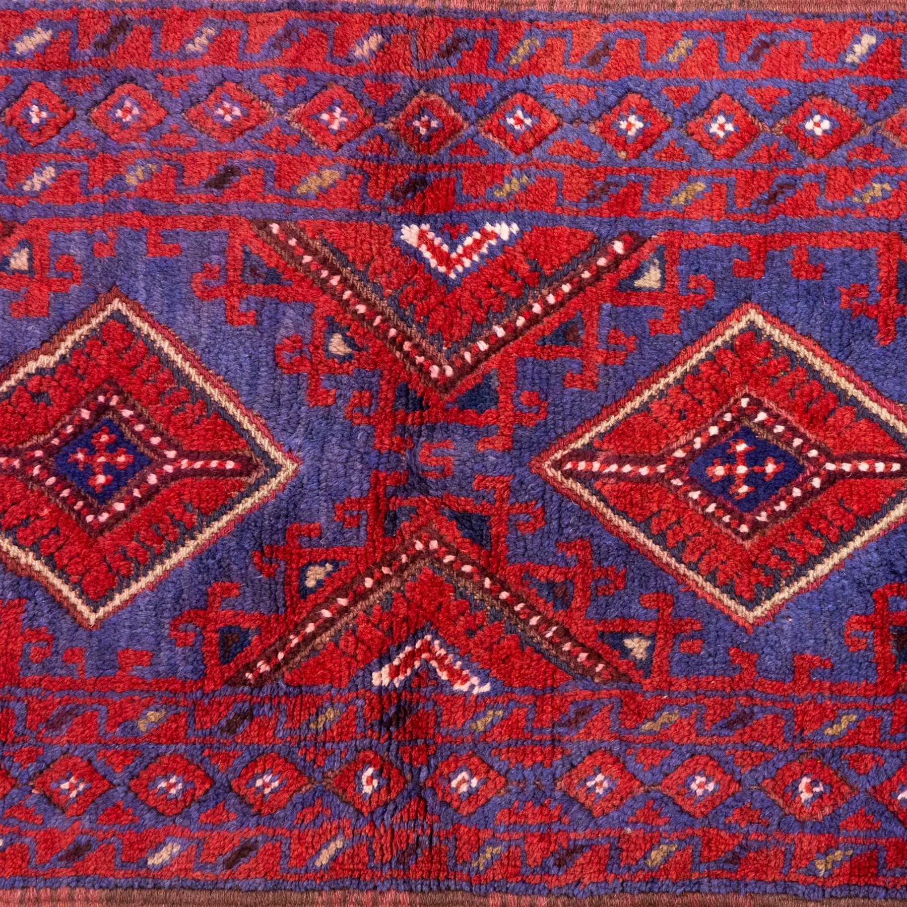Afghan Meshwani runner, hand-knotted wool pile, indigo ground decorated with a vertical series of angular diamond medallions in tones of madder red, dark blue, framed by geometric borders with flatwoven kilim ends with fringe 