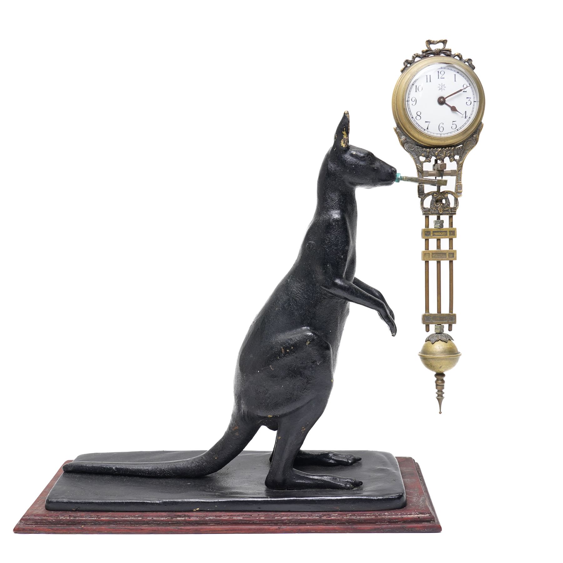  20th century-8-day Marsupial mystery clock with a cast brass patinated model of a standing Kangaroo on a wooden base, with a swinging compound pendulum resting on two steel pivots, white dial with Arabic numerals, minute track and steel spade hands, wound and set from the rear.