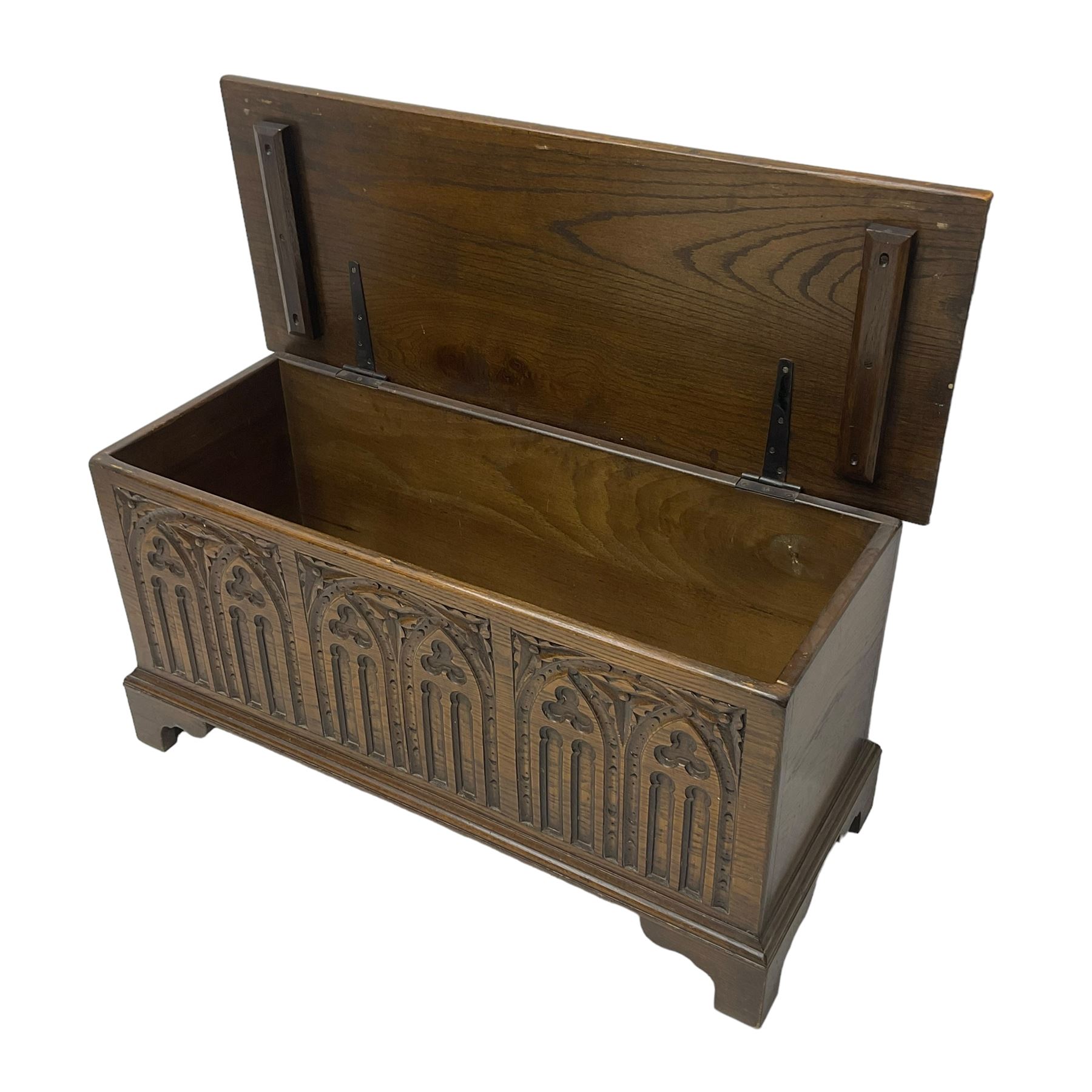 Mid-20th century oak blanket box, hinged lid over front carved with Gothic tracery work and flower heads, on bracket feet