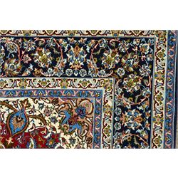 Fine Central Persian Isfahan hand-knotted rug, madder red field with central finely drawn foliate medallion issuing an intricate all-over scrolling vine design with palmettes and arabesques, enclosed by multiple conforming borders in navy ground, signed Isfahan in cartouche, silk fringe ends 