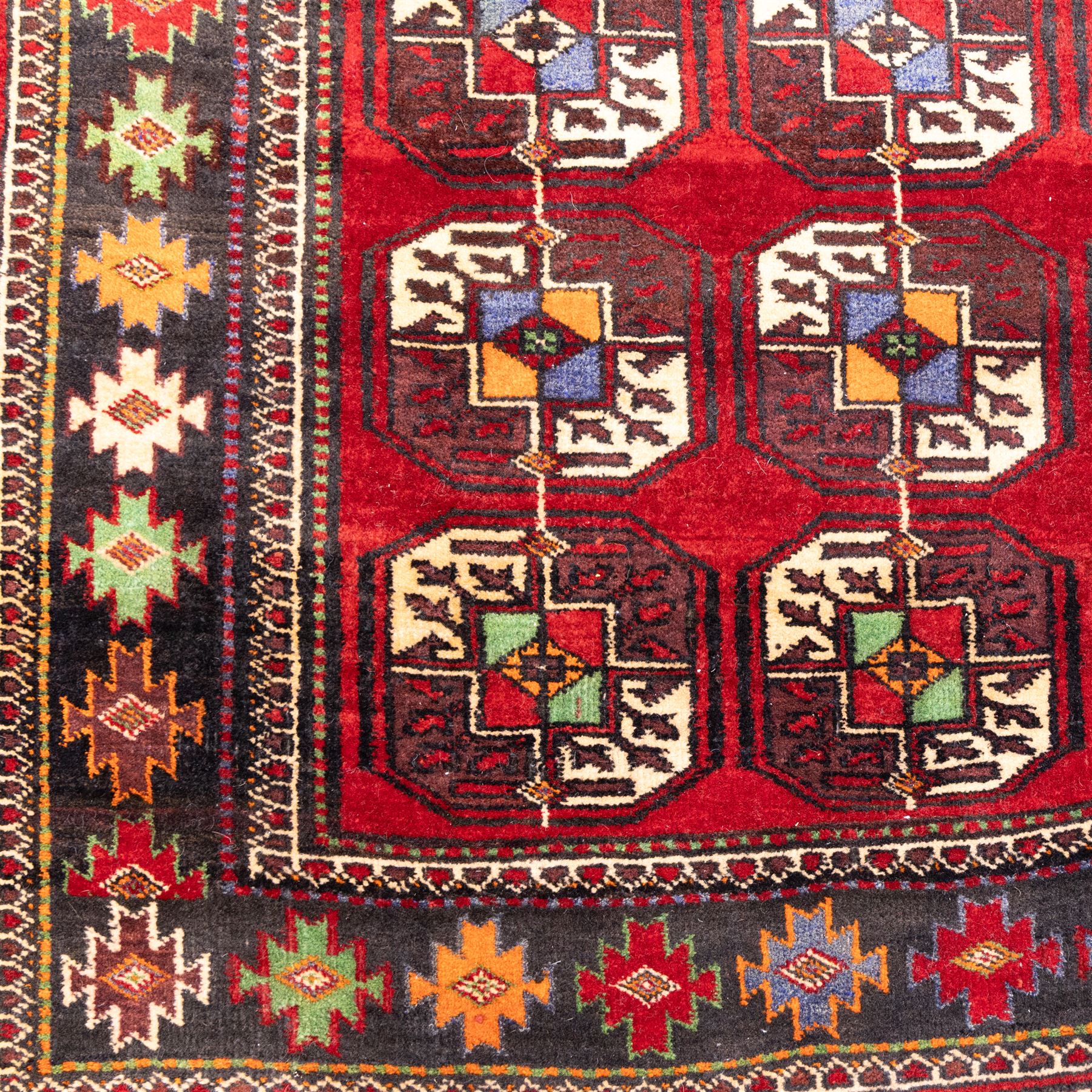 Tekke Bohara hand-knotted rug, madder red field decorated with an all-over design of repeating octagonal guls and latch-hook motifs within multiple geometric borders and cotton fringe ends 