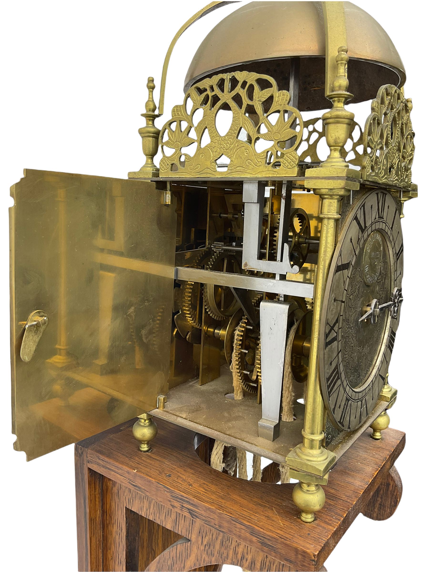 A 20th century replica of a 17th century 30-hour lantern clock with a rope driven verge escapement and countwheel striking, sounding the hours on a bell, with an engraved dial centre, silvered chapter ring and Roman numerals , half hour and quarter hour markers and a pierced and fettled steel hand, with an attached disc engraved “ Clockmaker In Scarborough Ivan Coe, Fecit,”, with engraved side doors, brass finials and dolphin fretwork, on a wooden bracket with pulley.   No weight.
Clocks similar to this were usually individually constructed by engineers working from plans of clocks designed by Claude Reeve, John Wilding, Malcolm Timings and other well-known clockmakers/engineers. 
