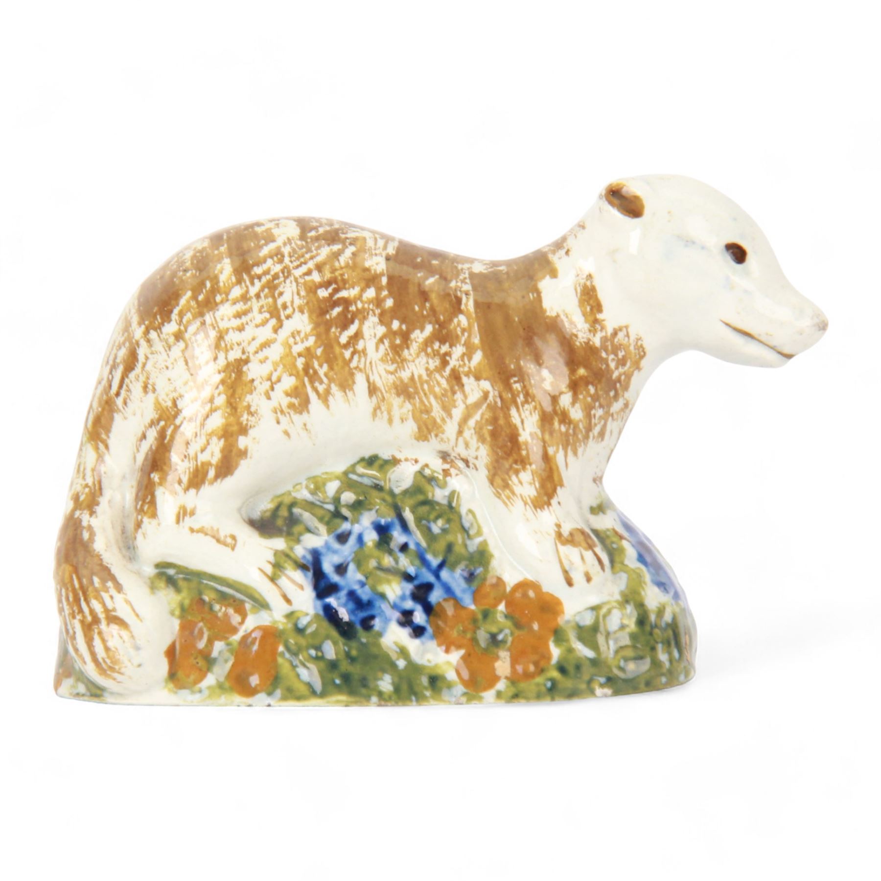 Late 18th/early 19th century Staffordshire model of a fox, the stalking fox decorated in Pratt type colours upon a green grassy mound base detailed with blue and ochre flowers, bearing Jonathan Horne labels beneath, H5.5cm L9cm

