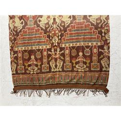 Ikat Man’s Cloth (Hinggi Kombu), East Sumba, Indonesia, woven in red, blue and yellow-brown warp ikat, constructed of two mirroring long panels, the motifs arranged in four bands depicting warrior figures astride rearing horses, high-ranking figures and guardians within geometric borders, on carved wooden wall hanger, L295cm
