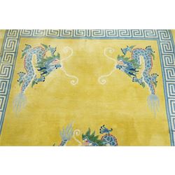 Modern Chinese hand-knotted wool pile carpet, golden field decorated with conforming dragons amidst stylized cloud scrolls enclosed by a Greek gey meander border, with cotton fringe ends 