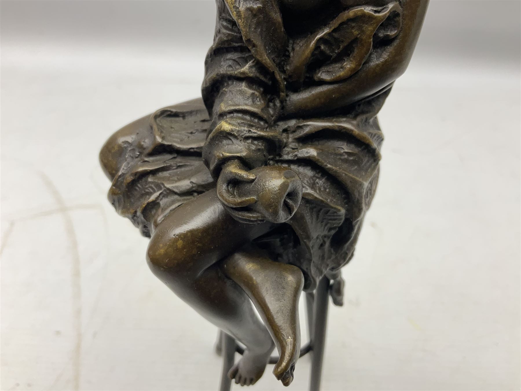 Art Deco style bronze modelled as a female figure seated upon a chair holding an apple, after 'Pierre Collinet', H28cm