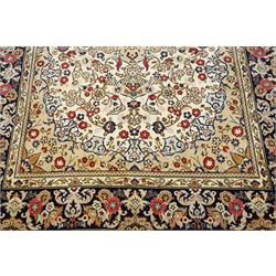 Central Persian Kashan hand-knotted carpet, ivory ground with a central floral medallion with an all-over design of scrolling vinery, palmettes, and flowering sprays i tones of madder red, cobalt, navy blue and sage green, with conforming spandrels, main border of deep indigo ground with repeating palmettes and stylized floral heads, flanked by narrow guard stripes, with cotton fringe ends, with cotton fringe ends 