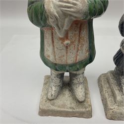 Three Chinese terracotta court attendant tomb figures, probably Ming Dynasty, two examples decorated in Sancai green glaze, the third example decorated in two tone blue glaze, each upon stepped square bases, tallest H22.7cm