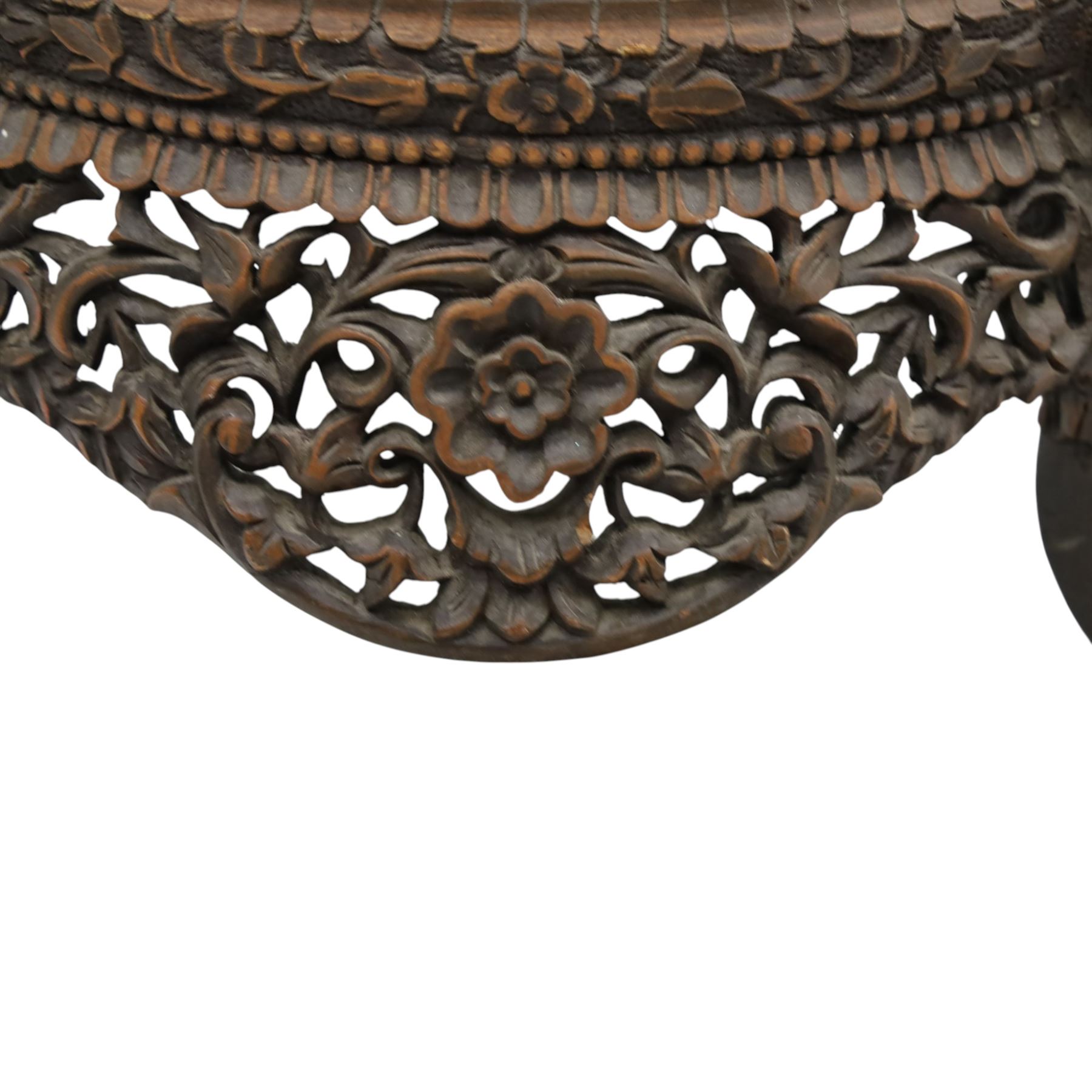 19th century Burmese carved hardwood jardinière stand, circular glazed top over pierced and carved floral frieze, on four zoomorphic supports carved with mythical beast masks and paw feet