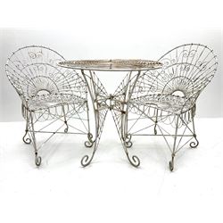 White painted scrolled wirework garden table (D77cm, H76cm), and two matching garden chairs