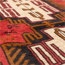 Turkish Anatolian rug, crimson ground, with stepped geometric medallions in ivory, brown, and black within angular striped borders in tones of red and ochre 