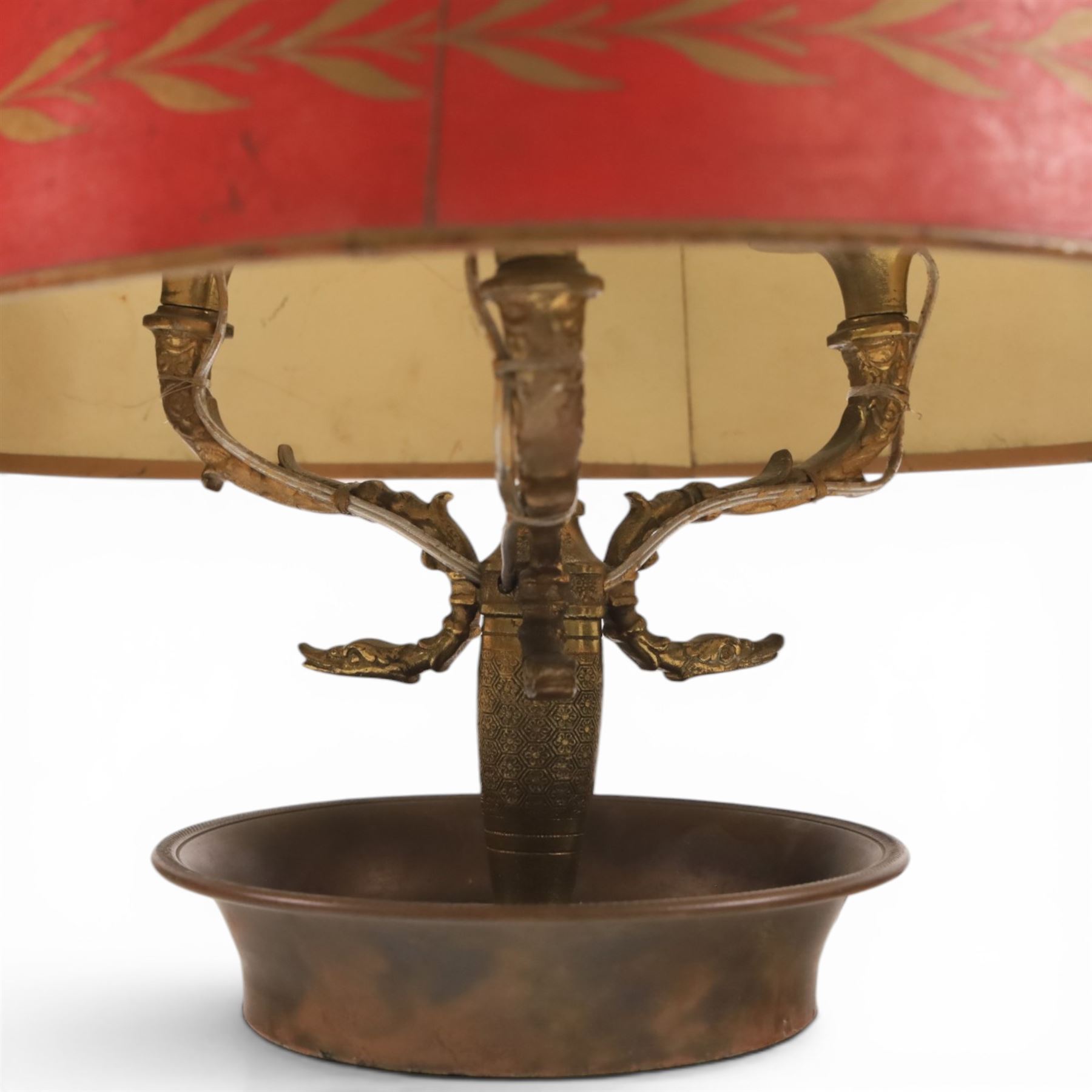 Bouillotte lamp, the adjustable red tole shade above three brass sconces upon a circular dished base, H54cm