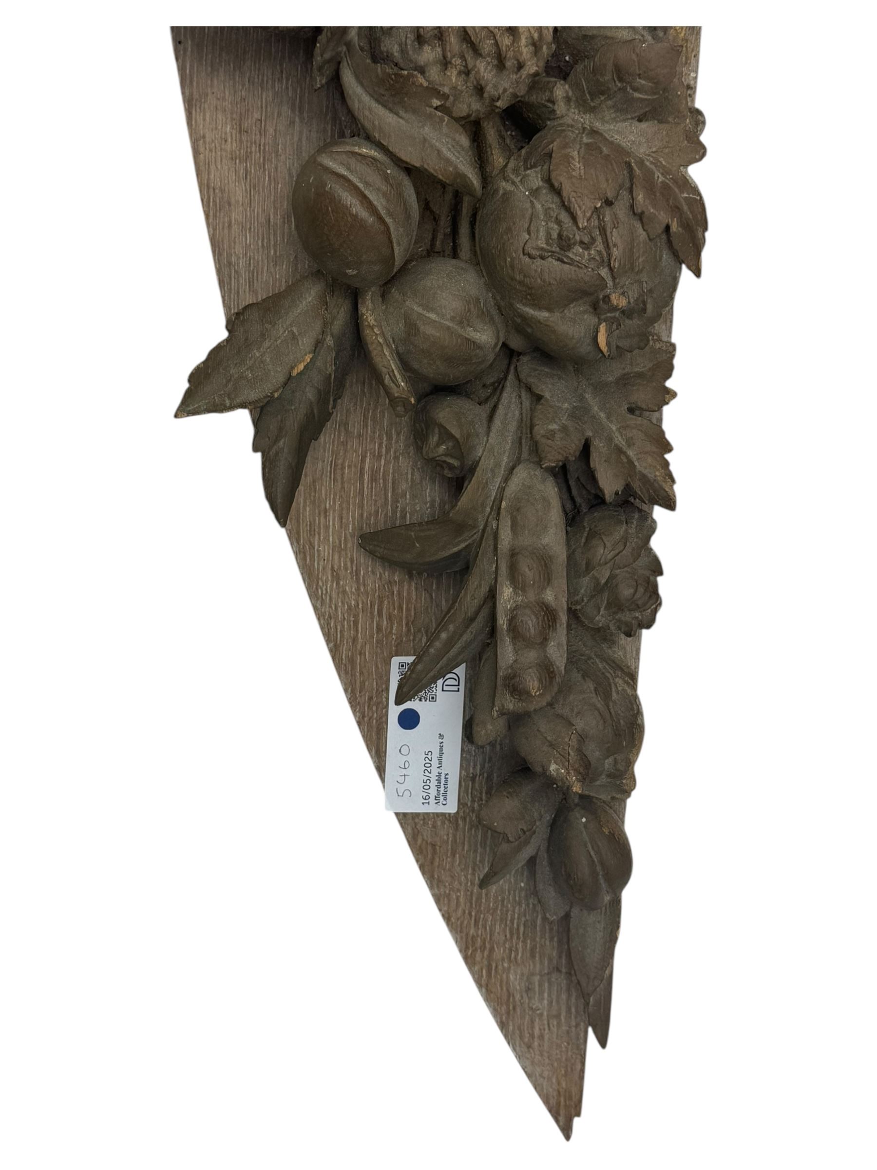 Early 20th century figural torchère, modelled as a standing putto supporting a circular top with tasselled drapery effect, raised on a circular base with foliate moulding; together with a 19th century large carved wood fragment, triangular form with high relief fruit, foliage and shell motif (H23cm, W129cm)