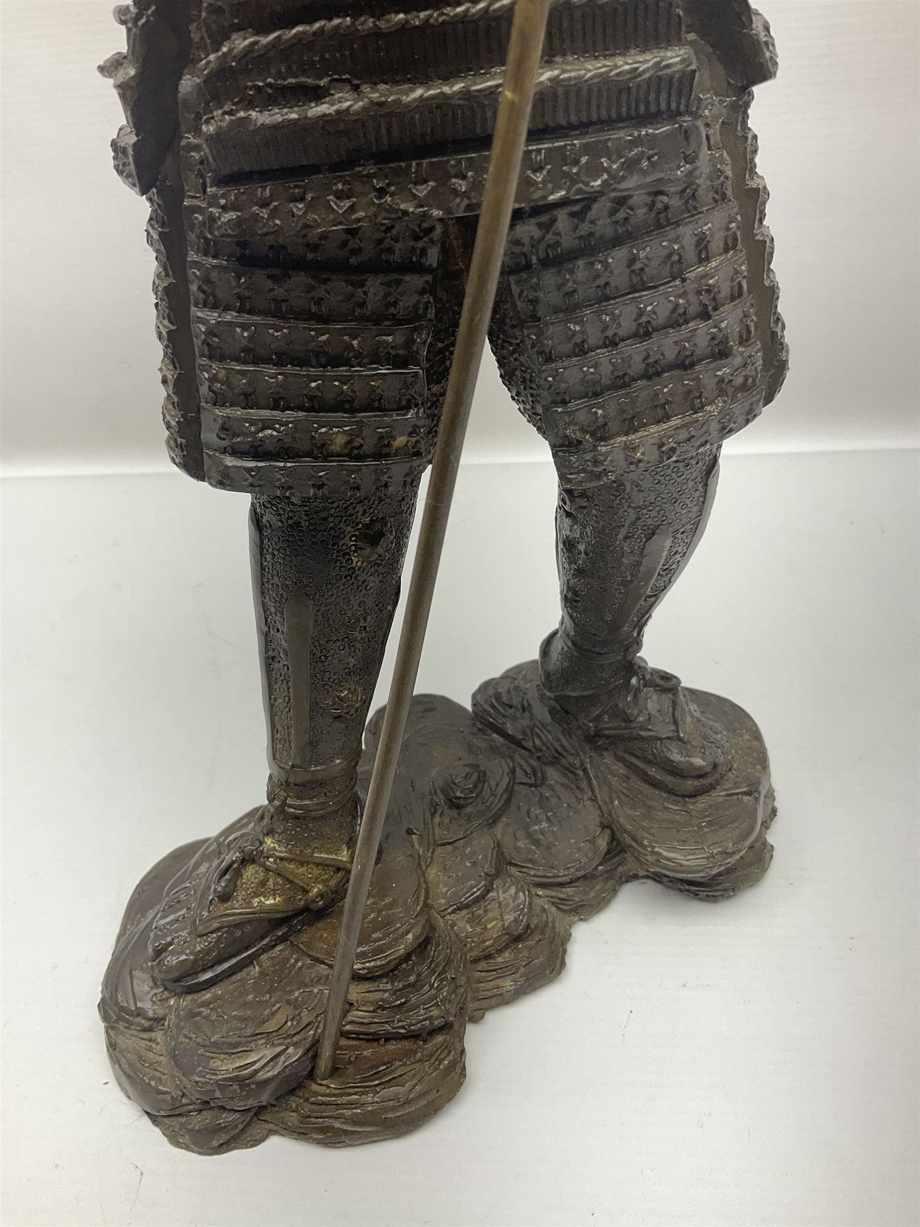 Bronze figure of a samurai standing wearing armour and holding a naginata, upon a rocky base, H48cm