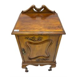 Edwardian Art Nouveau walnut bedside cabinet, raised broken swan neck back with carved flower heads, single fielded panelled door enclosing single shelf, raised on cabriole supports with ceramic castors