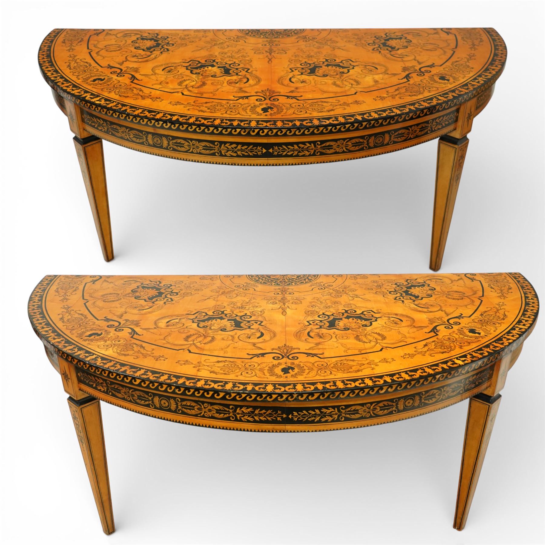 20th-Century Louis XVI-Style satinwood and penwork circular table or pair of console tables, the circular quarter-veneered top decorated in penwork with a central classical mask head motif within scrolling foliate and anthemion ornament on a contrasting black ground, above a conforming frieze decorated with Greek key-type scrolls. Raised on square tapering legs, each with an upper block panel decorated with compass-star motifs.