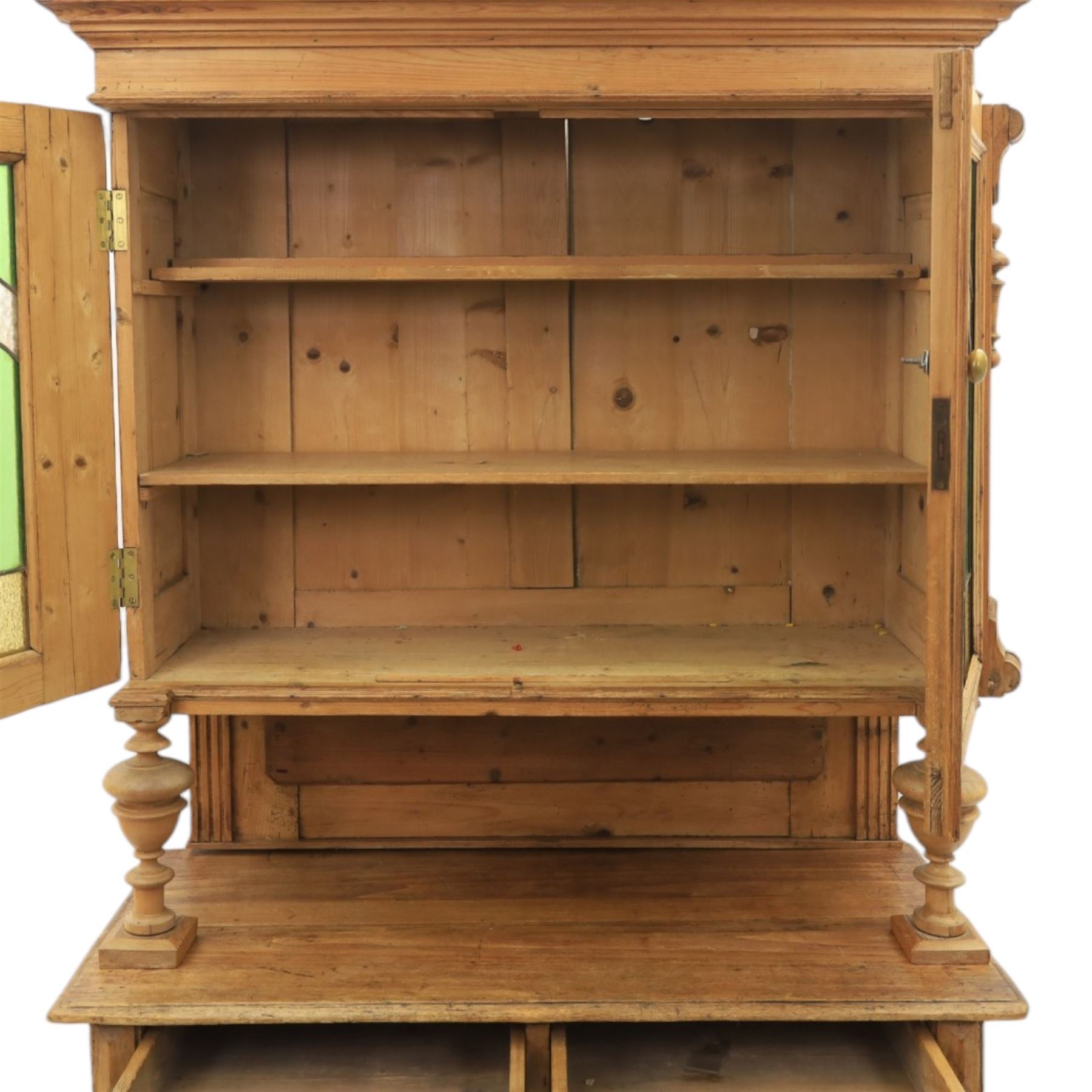 Late 19th century French pine dresser with stained glass upper section, the upper section with projecting cornice with fluted and scrolled details, enclosing a shelved interior, supported on turned front uprights, the lower section with frieze drawers and cupboard doors, raised on bun feet