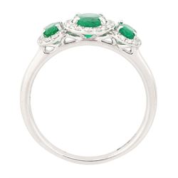Platinum emerald and diamond trilogy ring, three oval cut emeralds surrounded by round brilliant cut diamonds, hallmarked, total emerald weight approx 1.05 carat, total diamond weight approx 0.25 carat