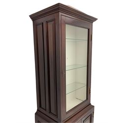 Mahogany display cabinet with hidden compartment, projecting cornice over single glazed door enclosing glass shelves, double panelled cupboard below, the interior with button releasing sliding back compartment, on bracket feet