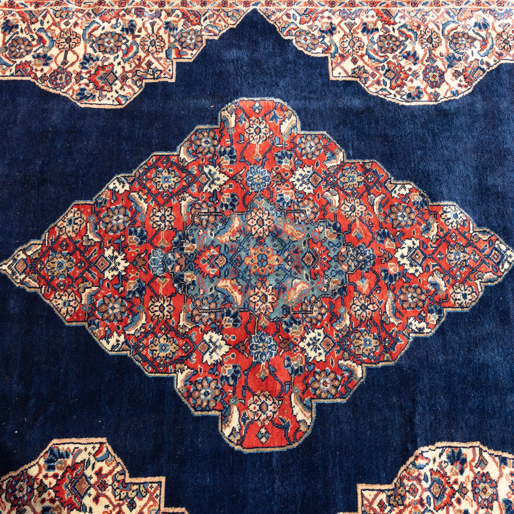 Large West Persian Bidjar hand-knotted carpet, deep indigo field with central medallion with pendants issuing an all-over design of scrolling vines, palmettes, and floral sprays, within conforming spandrels, enclosed a broad madder red palmette, and vine border framed by guard stripes, in a palette, of indigo, madder red and ivory tones, with cotton fringe ends 