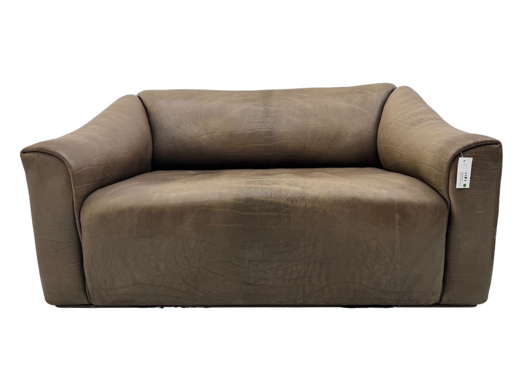 Mid-20th century two seater sofa, upholstered in soft brown leather with visible patina, curved arms and low back, on concealed supports (W138cm, D86cm, H72cm); matching armchair (W84cm, D86cm, H72cm)