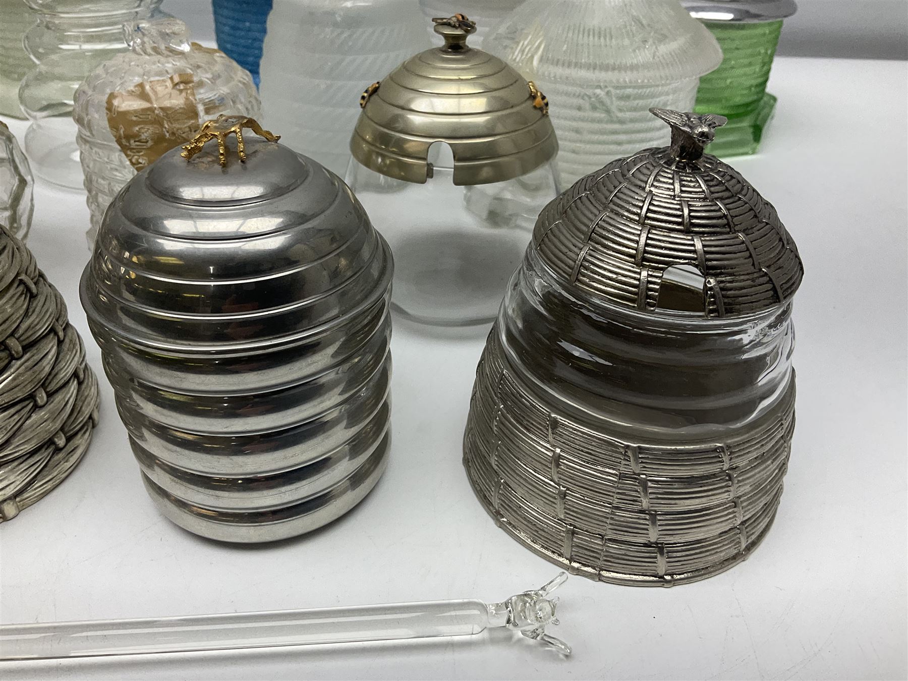 Collection of glass beehive honey pots, to include a blue slag example, milk glass, pink, green, etc together with four white metal examples (16) 