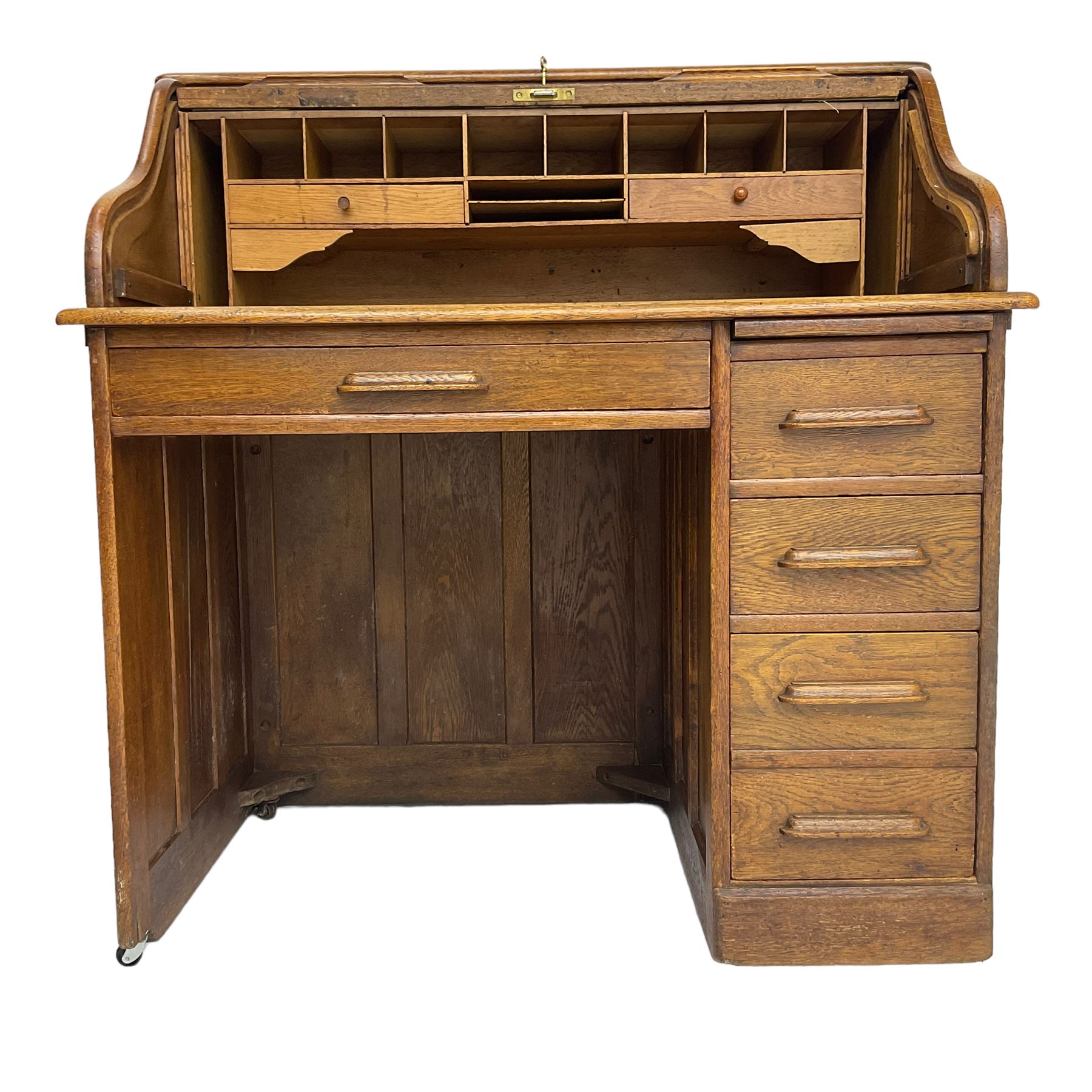 Early 20th century oak roll-top desk, the tambour enclosing pigeon holes and small drawers, the base fitted with slide, a single long drawer and three smaller drawers