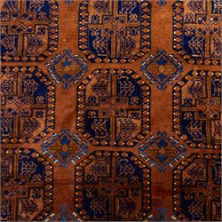 Pakistani Bokhara hand-knotted carpet, camel field decorated with rows of large tekke style octagonal guls enclosing stylized geometric motifs, interspersed with small stepped diamond devices within multiple geometric borders, with fringe ends 