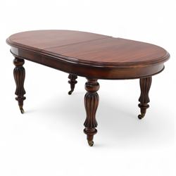 Victorian mahogany extending dining table, rounded rectangular top with moulded edge, pull-out action fitted with two additional leaves, raised on four reeded and fluted baluster legs with brass caps and castors