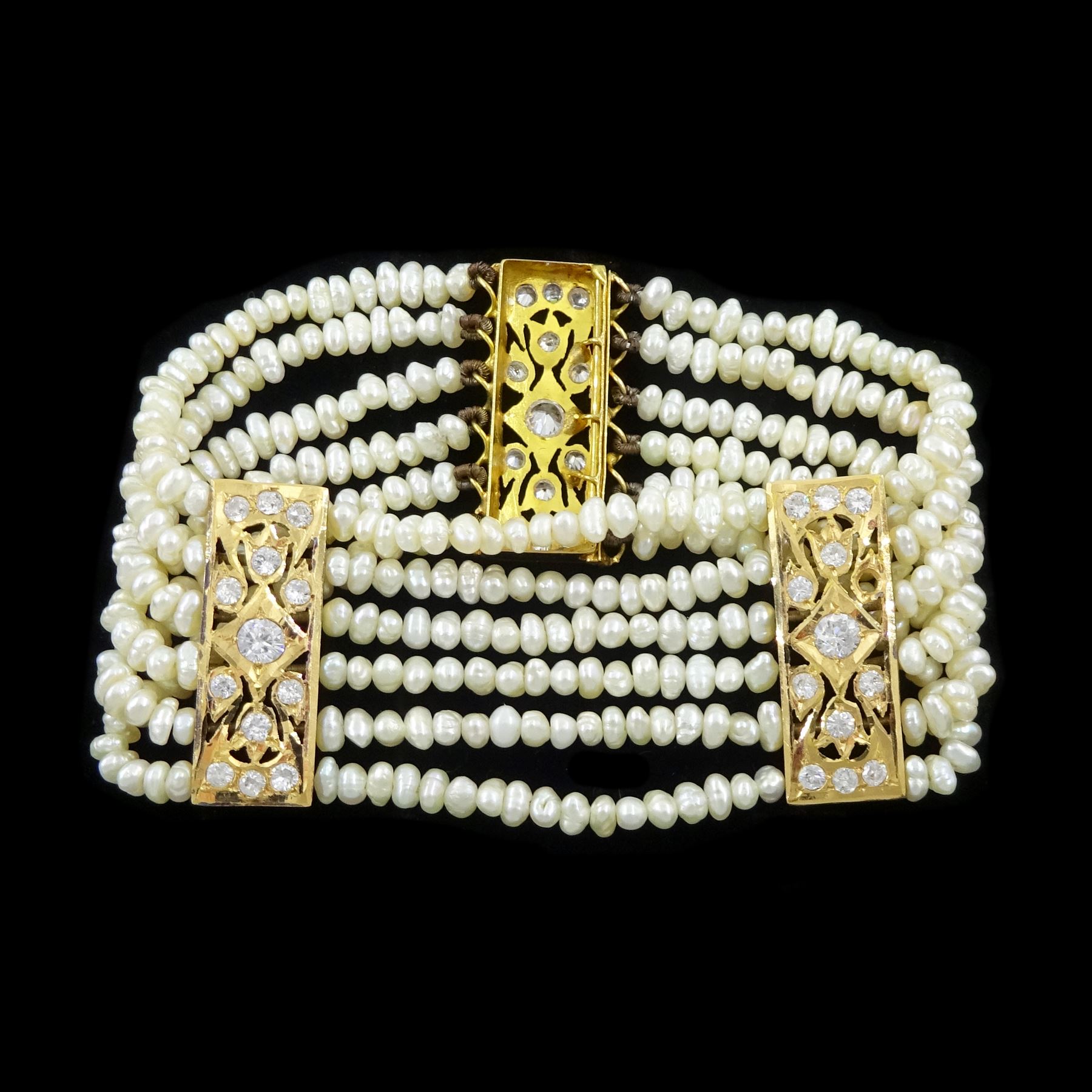 18ct gold pearl and white paste stone bracelet, six strands of cultured white pearls, spaced by openwork gold panels set with paste stones
