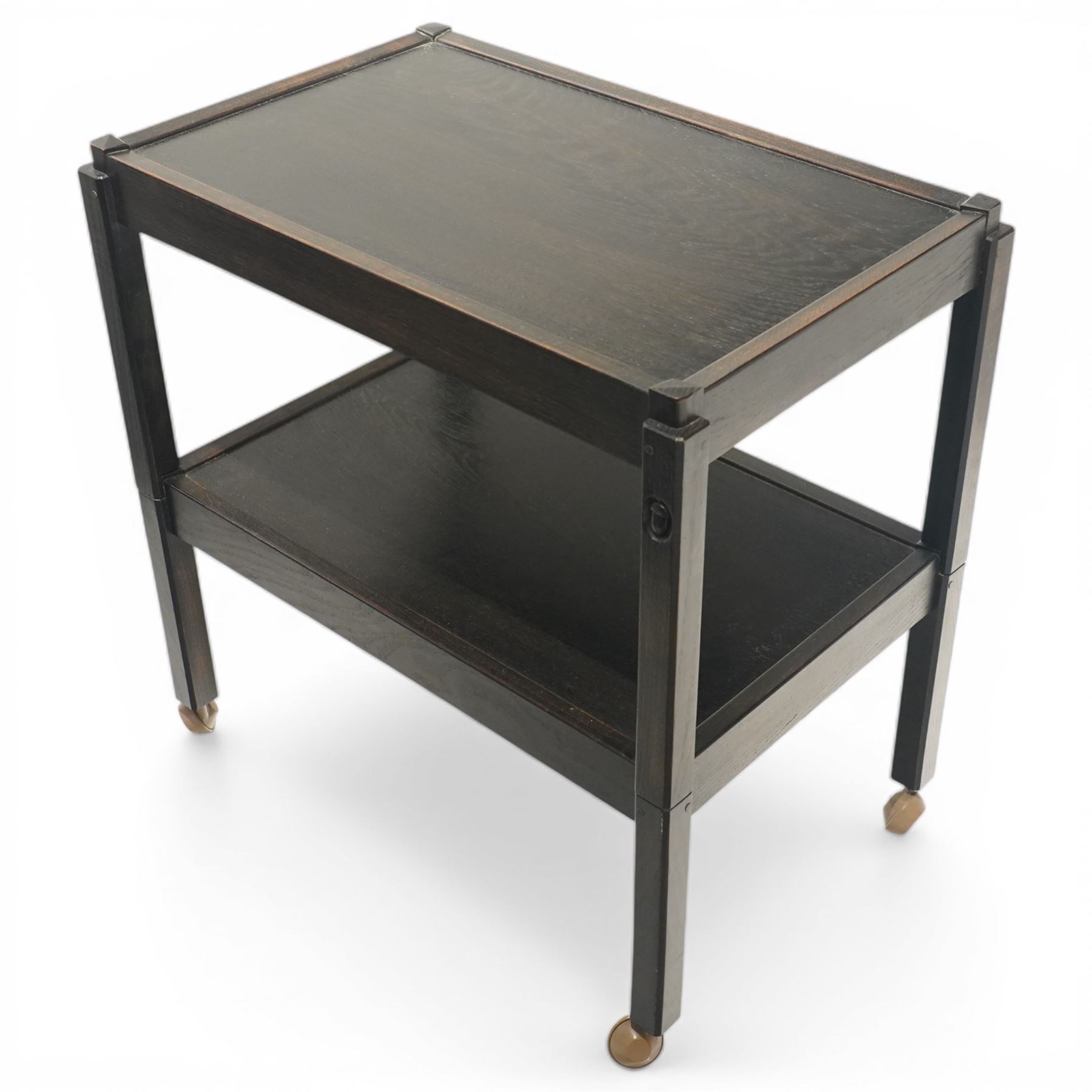 Acornman - dark stained oak two-tier stacking tea trolley, the rectangular removable top, above a second tier raised on castors, with carved acorn signature, by the workshop of Alan Grainger of Brandsby
