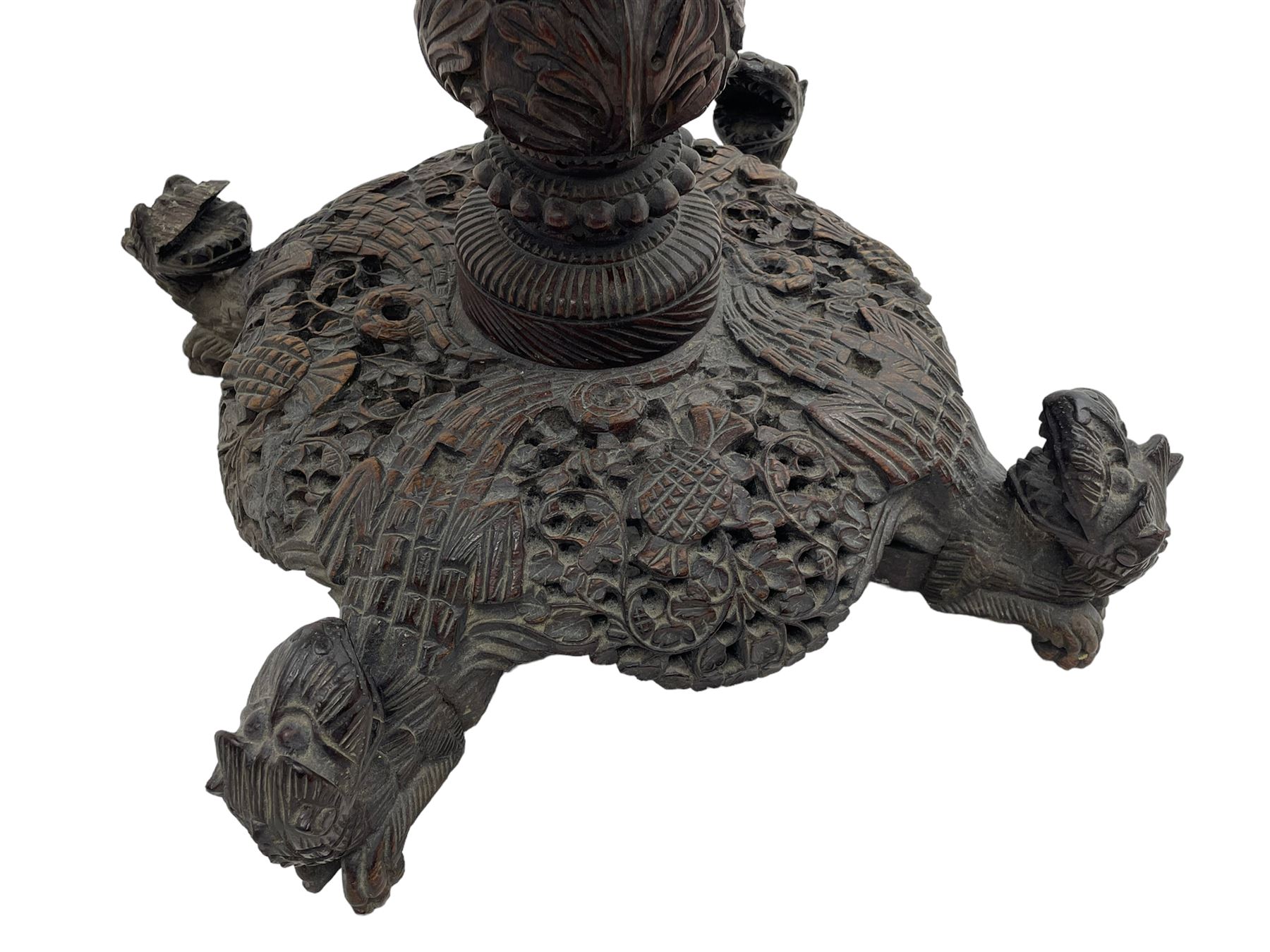 Late 19th century Anglo-Indian carved hardwood occasional table, circular tilt-top carved profusely with mythical animals and foliage decoration, pierced and carved with interlaced leafy branches, leaf carved pedestal supports on a raised platform with further carved and pierced foliage decoration, four carved feet in the form of mythical beasts with gaping jaws 