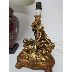 Ceramic table lamp, decorated with gold leaves on a red ground, together with a pair of figural table lamps, modelled as a group of putti, in a gilt finish on wooden base, tallest H62cm