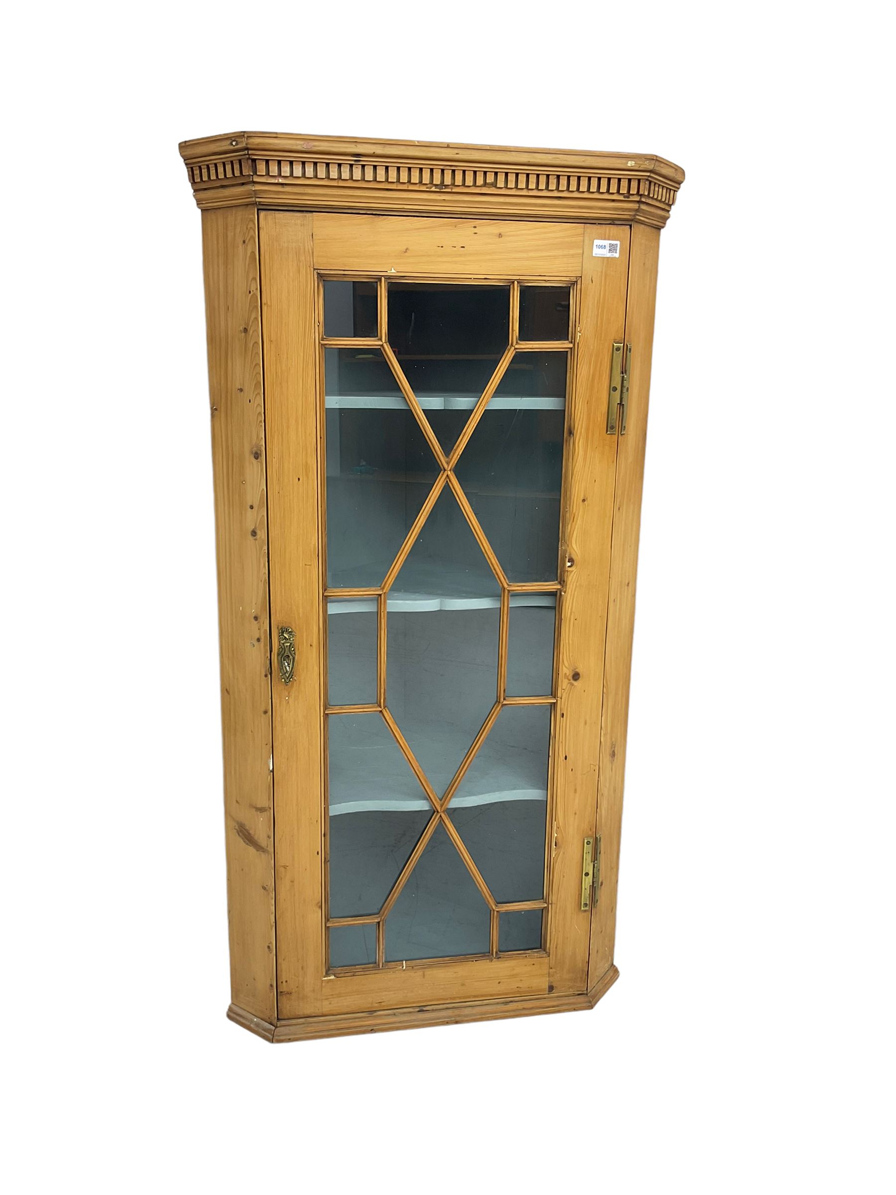 Early 19th century pine corner cabinet, projecting dentil cornice over astragal glazed door