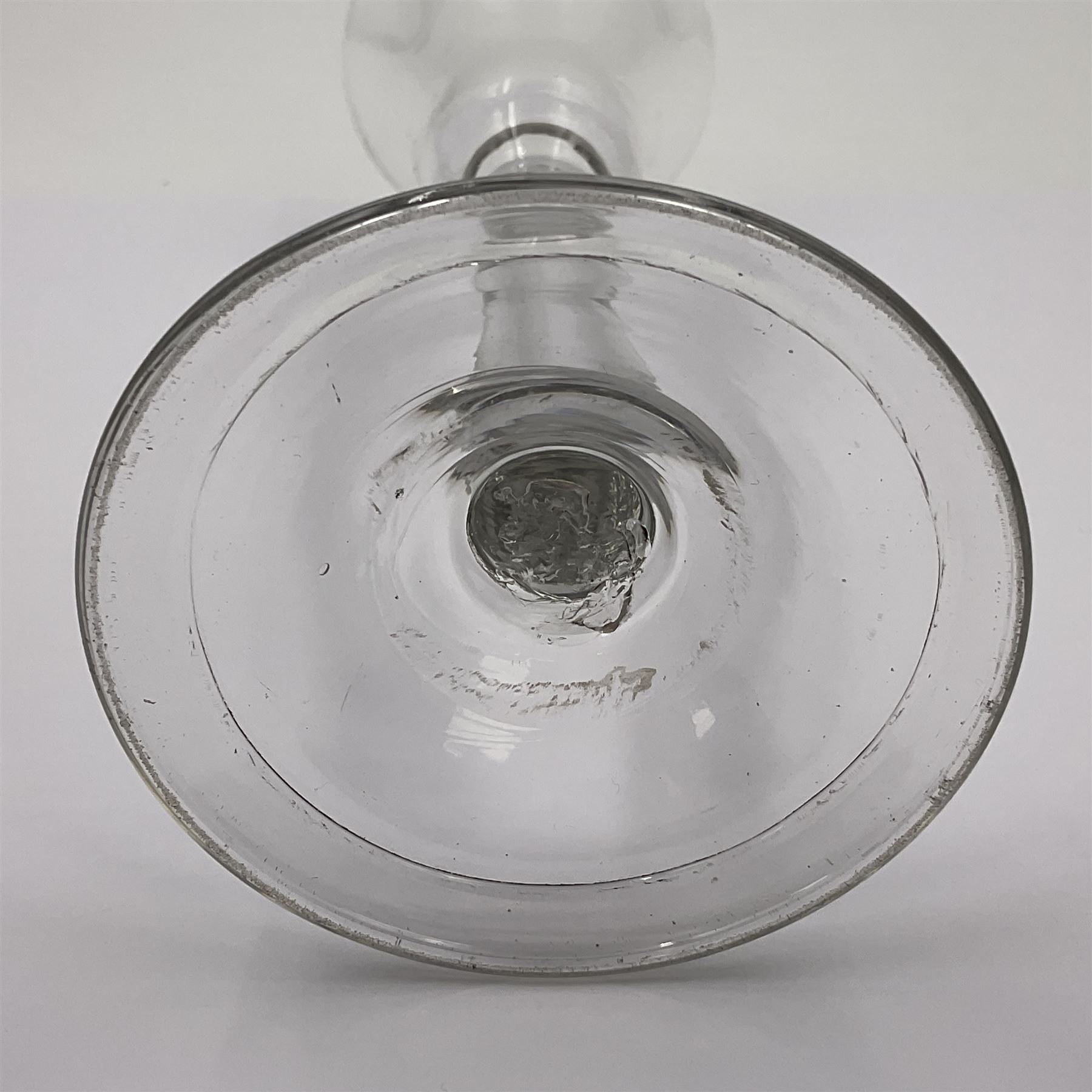 Three 18th century wine glasses comprising a plain stemmed glass with bell shaped bowl and conical folded foot H16cm, another plain stemmed glass with ogee bowl and folded foot and a Continental glass with gilt faceted bowl, decorated with male figure within a landscape, on a clear Silesian seven sided cut stem (3)