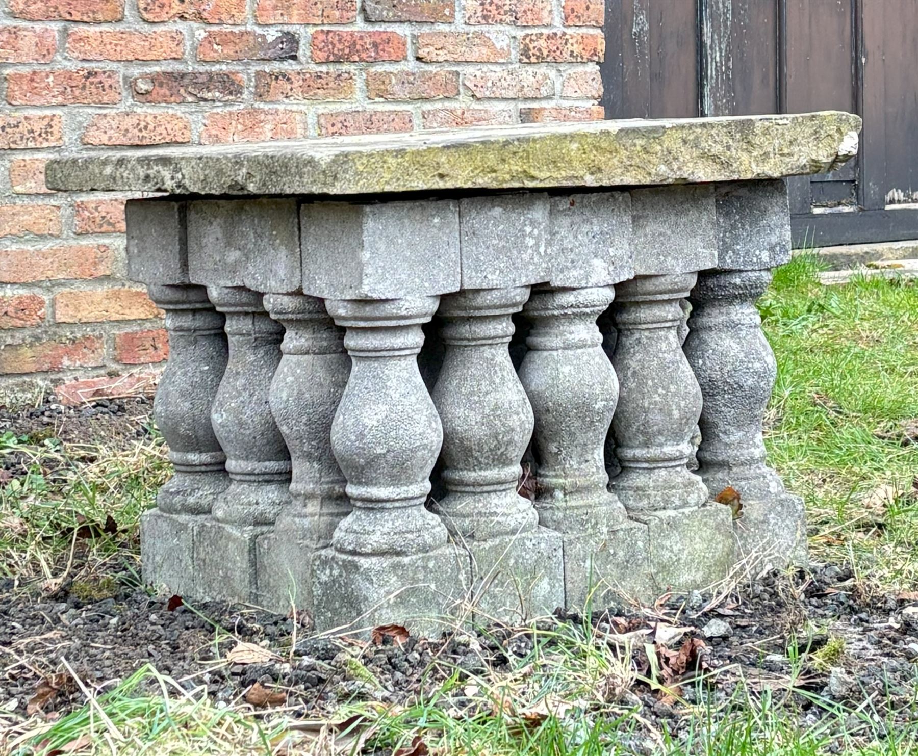Weathered stone garden table, comprising twenty reconstituted stone balustrades supporting a stone flag top. H55cm, 63cm x 77cm.  - COLLECTION BY APPOINTMENT FROM: The White House, Thirsk Road, Easingwold, York, YO61 3NF - CALL 01723 507111 TO ARRANGE