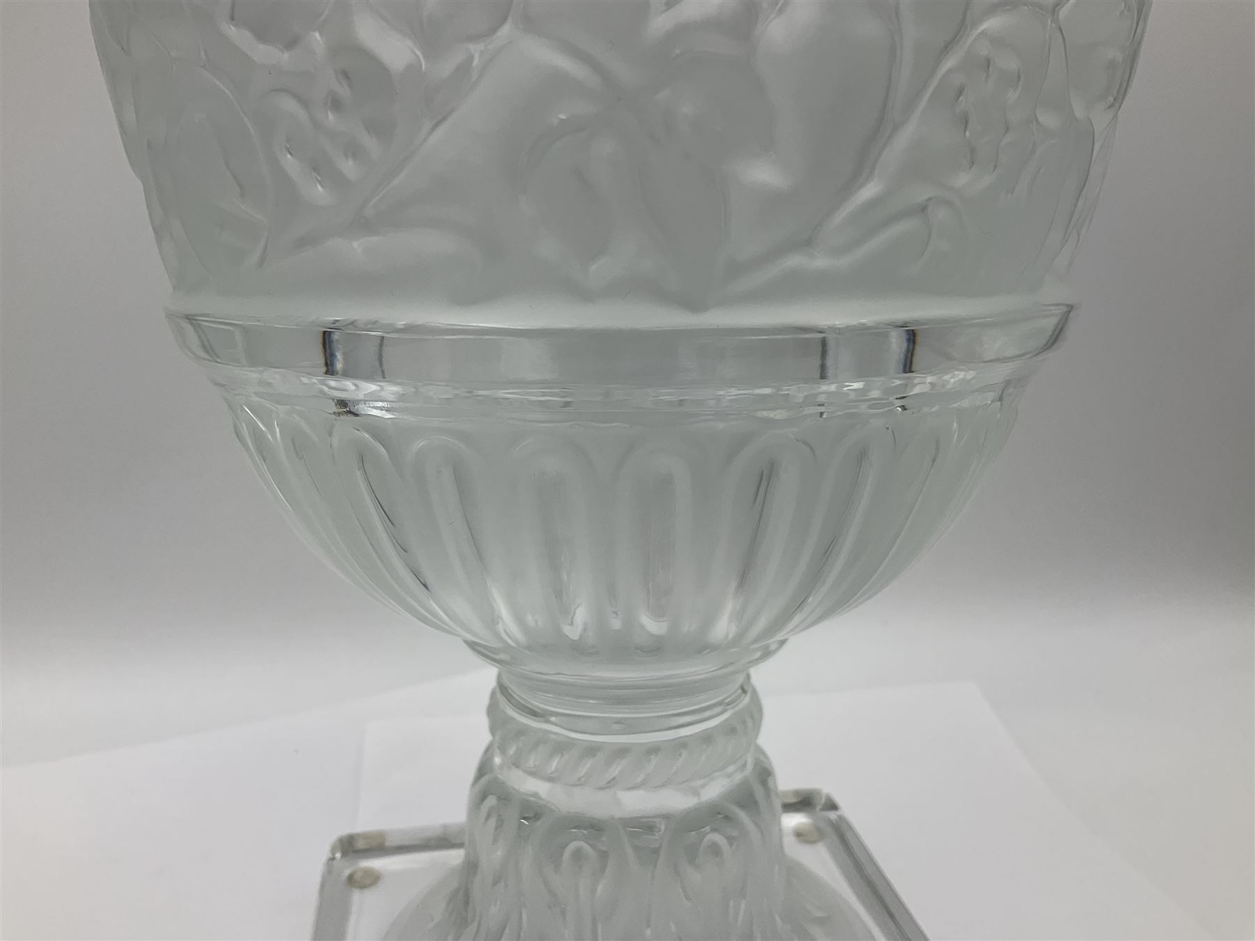 Large and impressive Lalique Versailles pattern glass vase, of classical baluster form with gadrooned flared rim, the body moulded in relief with fruiting vines above part fluting, upon a spreading circular foot with moulded decoration, and plain square plinth base, signed Lalique France to side of plinth, overall H35cm, with original box 