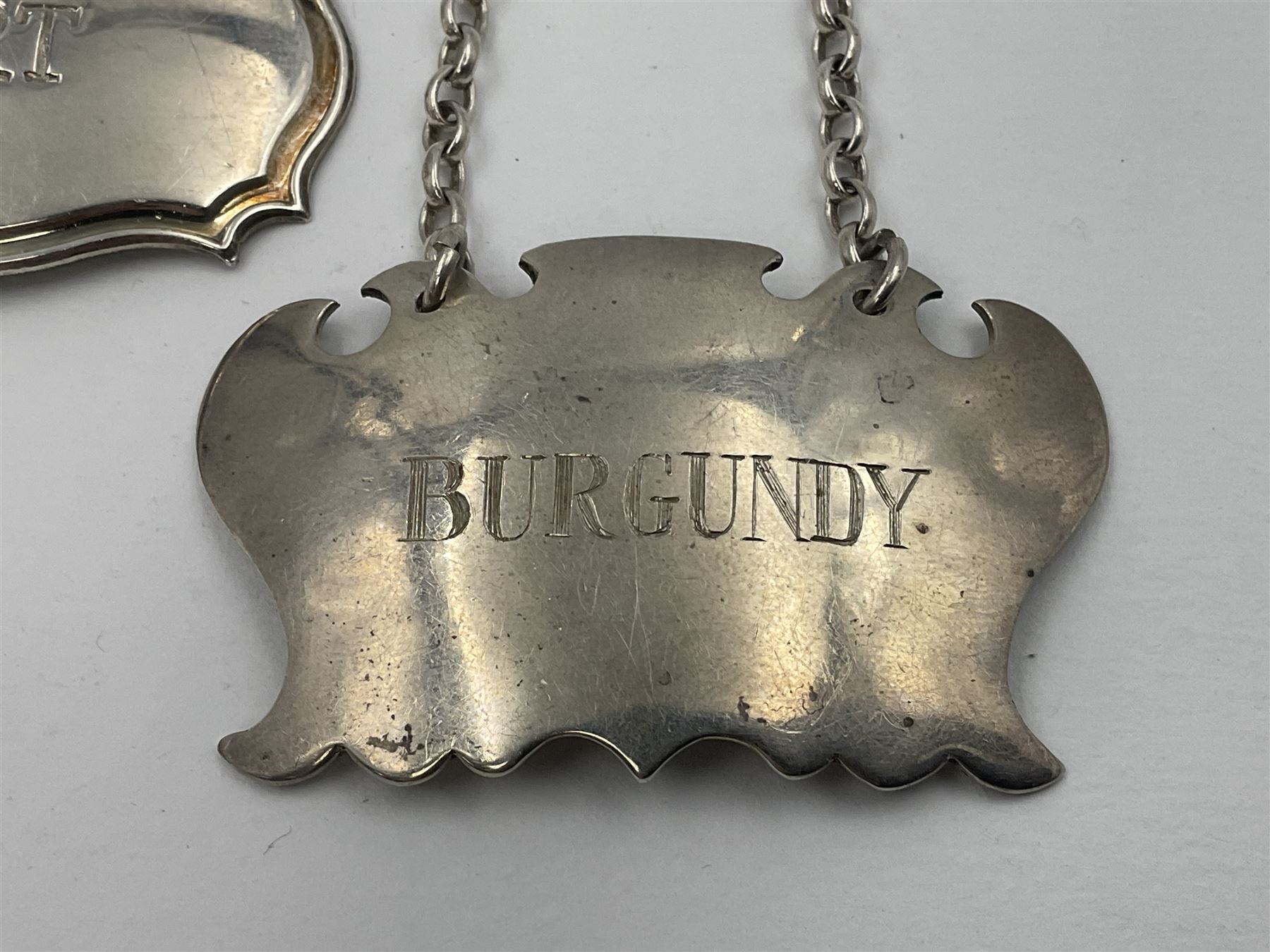 Five modern silver decanter labels, to include two sherry examples, embossed with scrolls and fruits, hallmarked W I Broadway & Co, Birmingham 1991 & 1997, a similar claret example, hallmarked S J Rose & Son, Birmingham 1973, and two plain shaped port and burgundy examples, hallmarked C Robathan & Son, Birmingham 1997 and A Haviland-Nye, London 1968