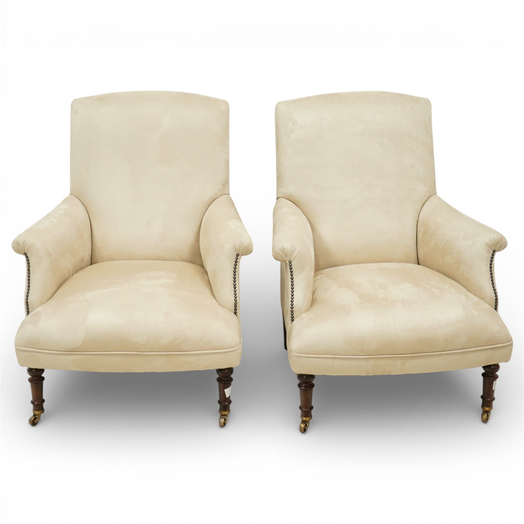 Sofas & Stuff - pair of ‘Thistle’ armchairs upholstered in neutral fabric, each with gently sloping back, padded scroll arms with close-set stud detailing, loose seat cushions, raised on turned wooden legs with brass castors