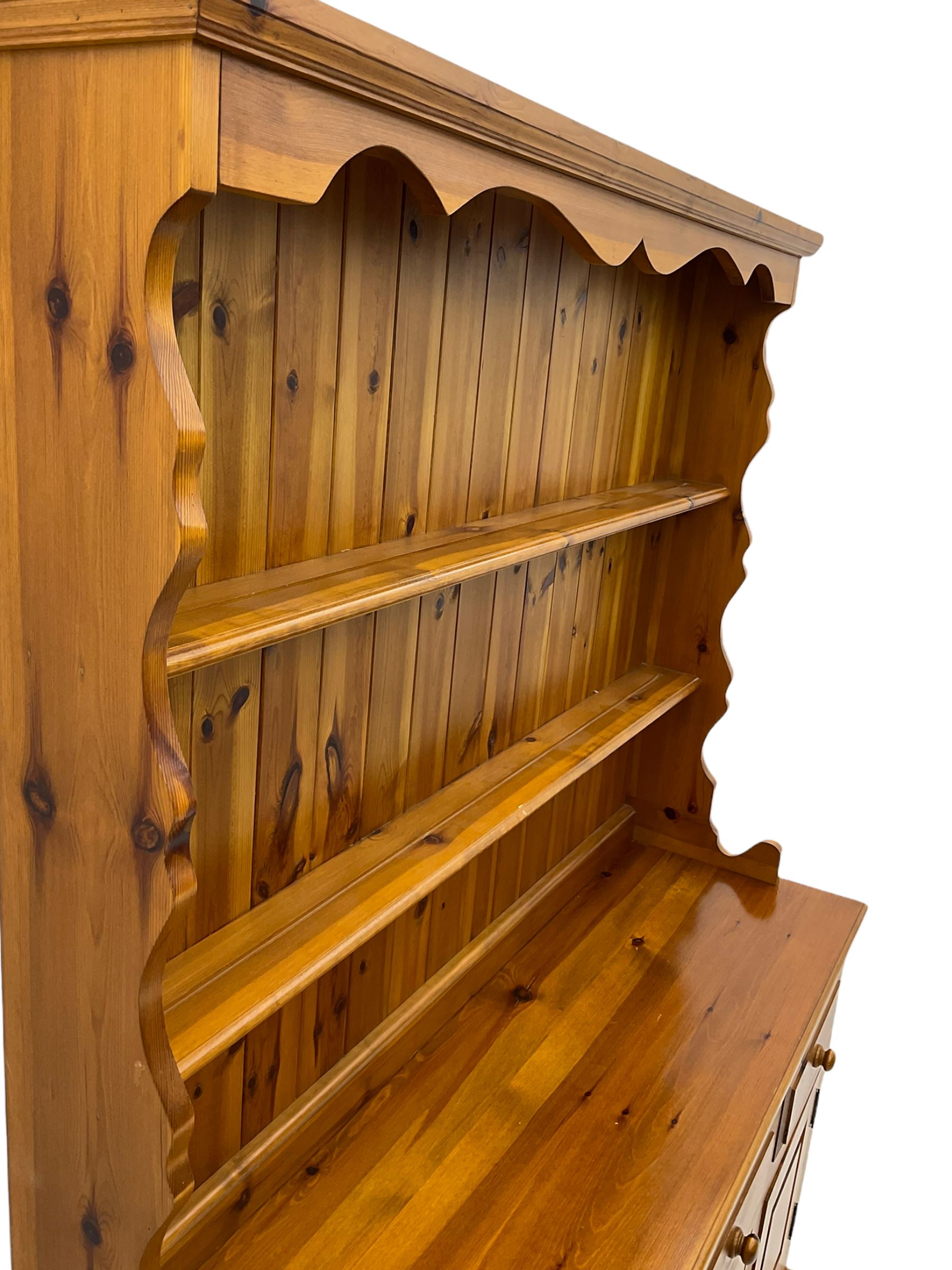 Pine farmhouse dresser with three drawers and three cupboards, and two tier plate rack