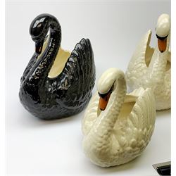 Four Dartmouth pottery jardinières or planters, modelled in the form of swans, comprising three white examples, and one black, marked beneath Dartmouth Devon England, larger examples H29cm, smaller examples H21.5cm. 