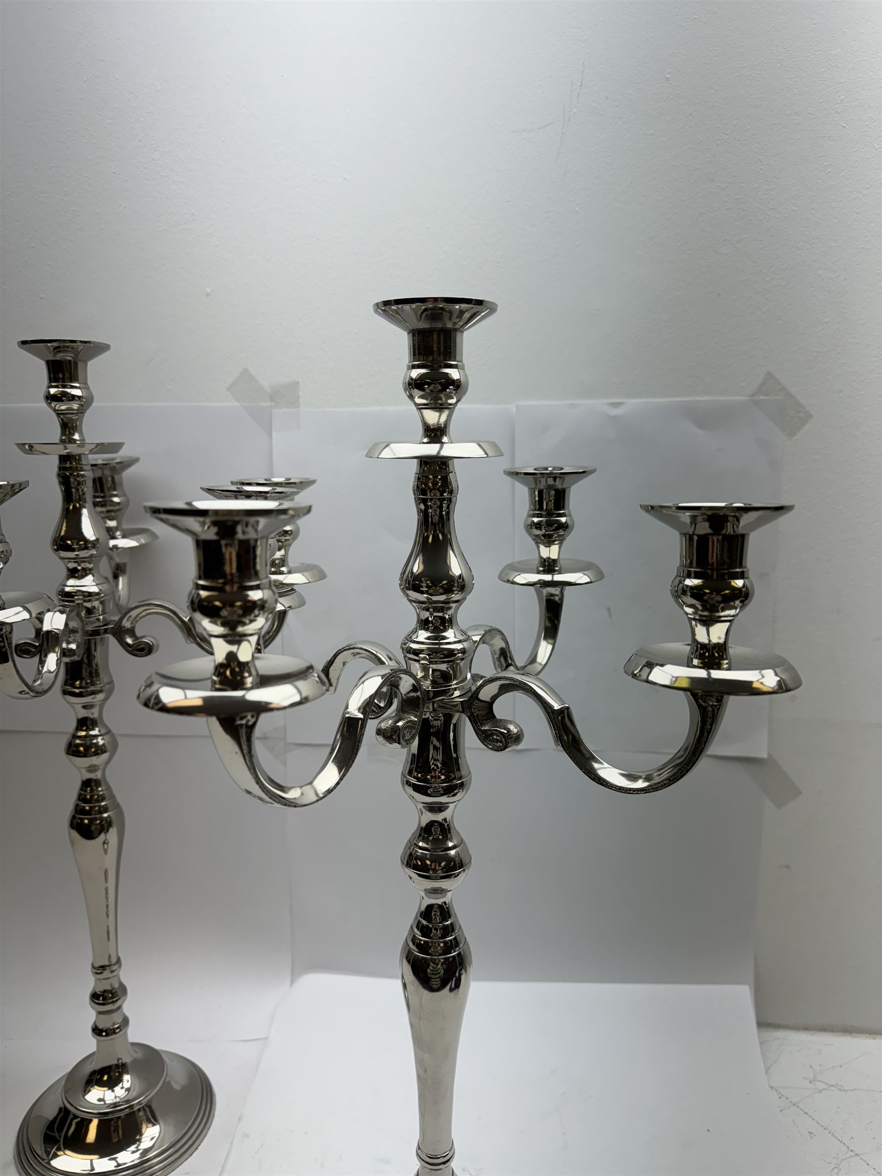 Pair of four branch candelabras, urn-shaped nozzles raised upon scroll branches supported from tapering central stem, with a stepped circular base, H59cm