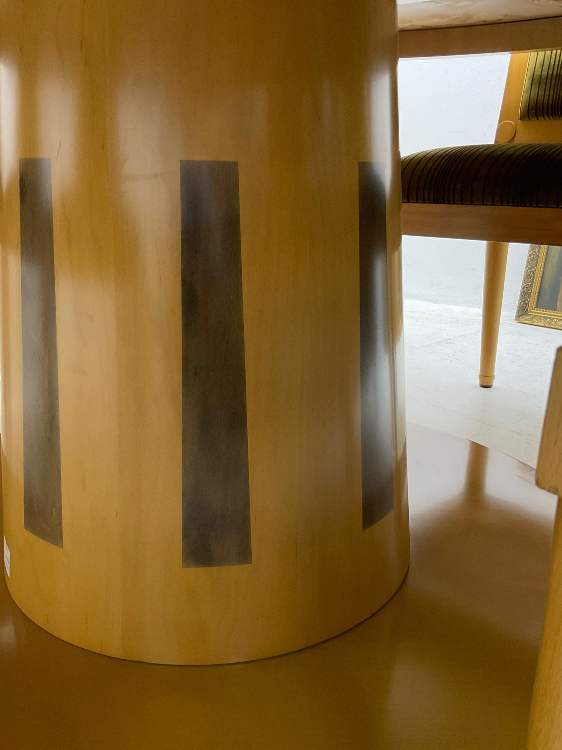 Contemporary beech and maple dining table, circular top on tapered cylindrical pedestal inlaid with rectangular panels, on circular base; together with set eight beech high back chairs upholstered in striped fabric, on turned supports 