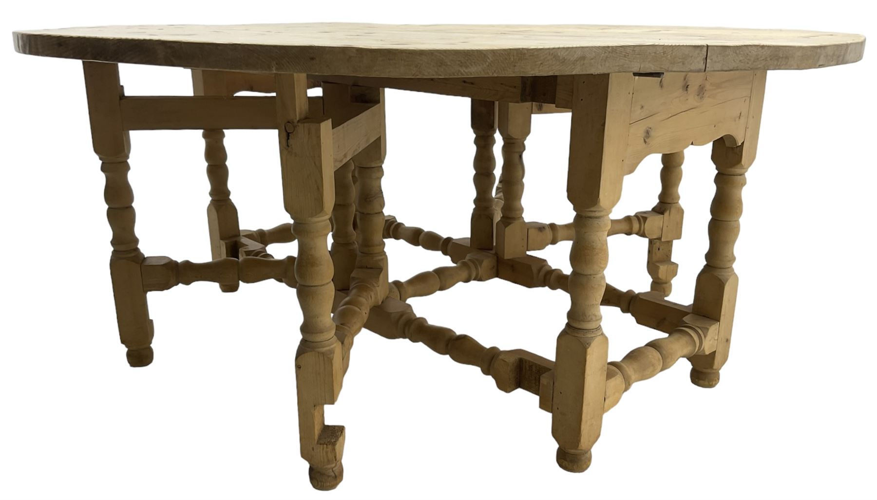 Traditional stripped pine dining table, circular drop-leaf top over double gate-leg action base with turned supports united by turned stretchers