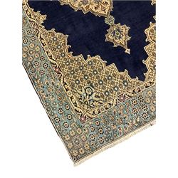 Central Persian Qum indigo ground rug with silk inlay, the plain field decorated with floral design medallion and lattice spandrels, the wide border decorated with trailing flowers and foliage 