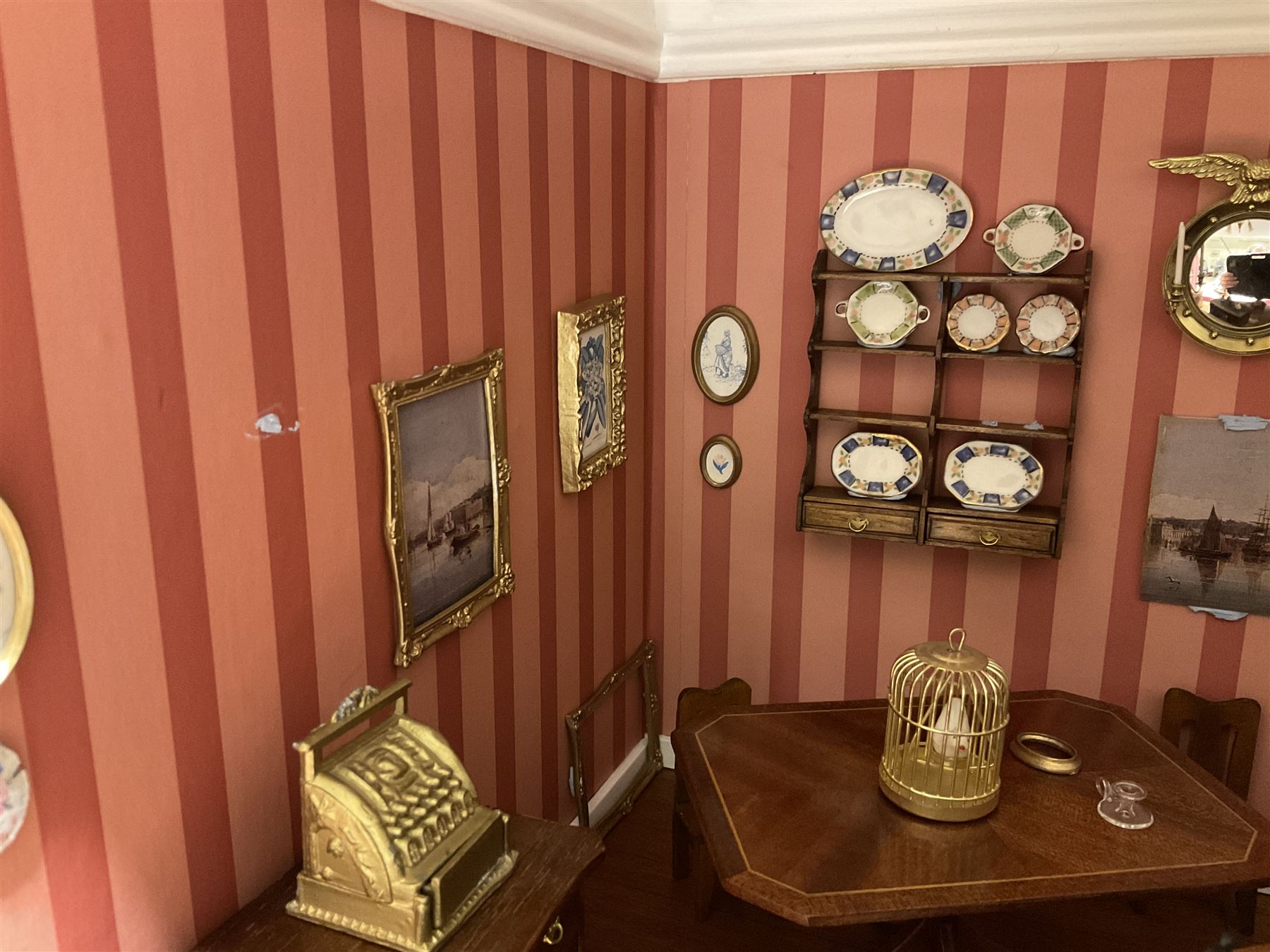 Good quality late 20th century dolls house by M. James dated 1995 in the form of a Beverley East Yorkshire Antique Shop called 'North Bar Antiques'; single-storey single-roomed shop with textured brick walls and flat roof, fully glazed hinged front with recessed hinged customer door and central window to the rear; comprehensively furnished with chests of drawers, pedestal desk, breakfast table, lowboy, two longcase clocks, delft rack with ceramics, occasional tables, pictures, Regency style mirror and collectibles; decorated walls with coving and picture rail and simulated floorboarding; wired for electric lighting; maker's plaque W61cm H42.5cm D41.5cm