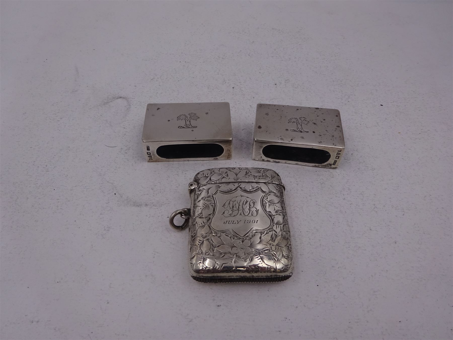 Pair of early 20th century silver matchbox covers, each of typical form, engraved with a tree to the centre, with personal engraving to reverse, hallmarked Stokes & Ireland Ltd, Chester, date letter worn and indistinct, together with a late Victorian silver vesta case, engraved with floral decoration, with monogrammed shield shaped cartouche to centre, hallmarked E V Pledge & Son, Birmingham 1900